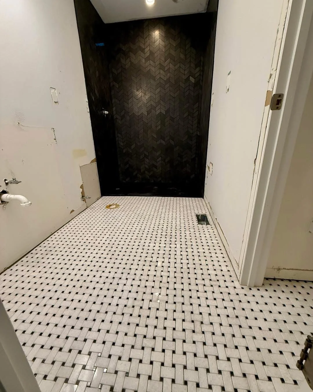 Bathroom with black herringbone shower tile and white mosaic floor