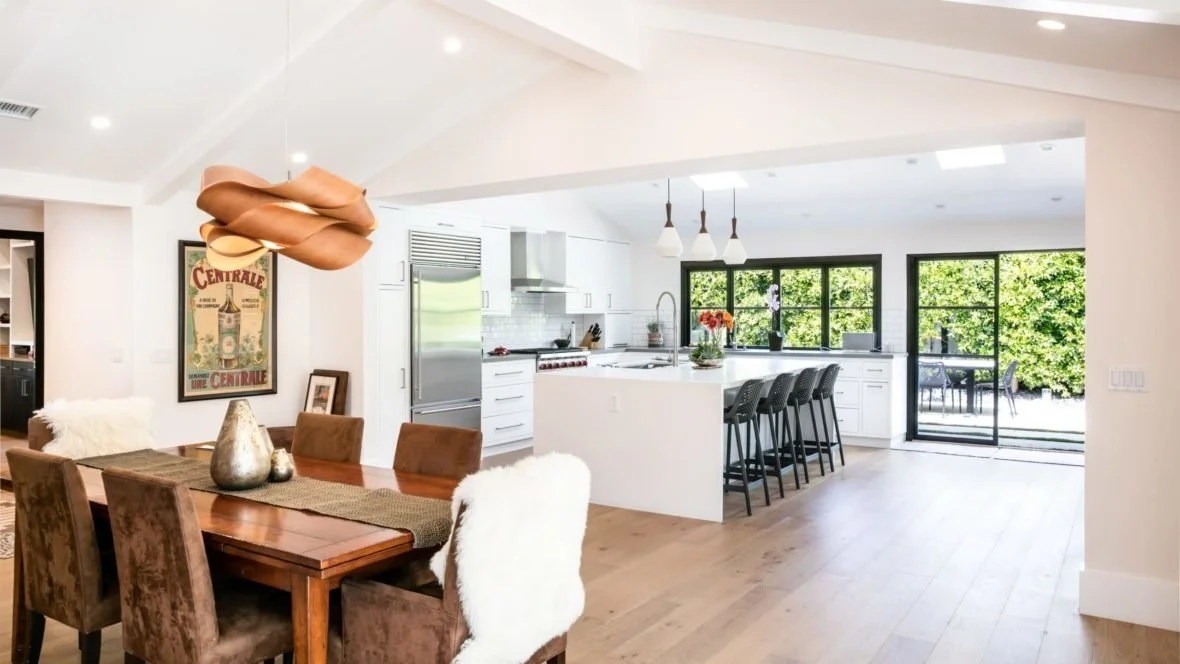 Modern kitchen with white cabinetry, island seating, and glass doors overlooking outdoor space