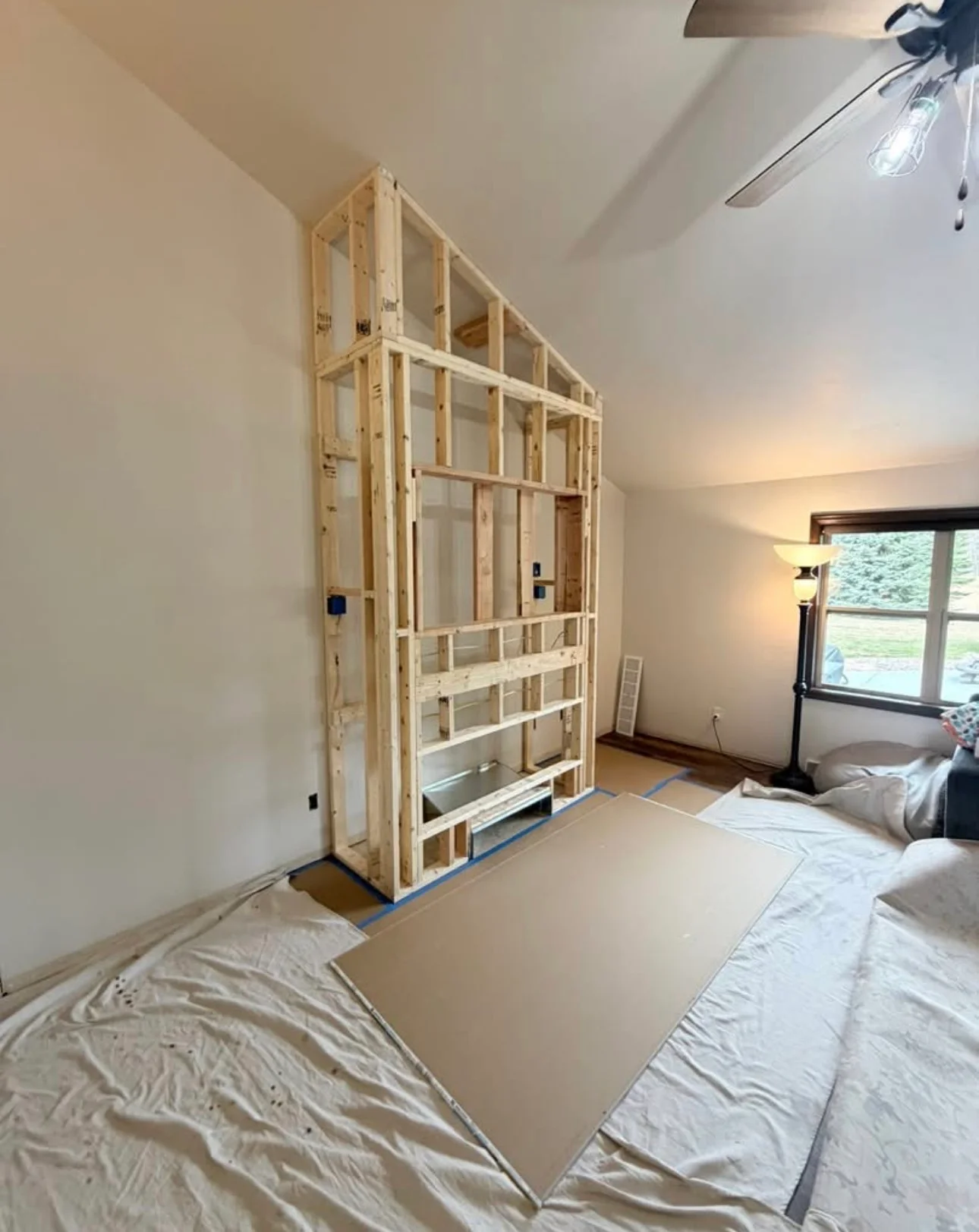 Wooden framing of custom built-in bedroom cabinetry with shelving compartments and electrical rough-in