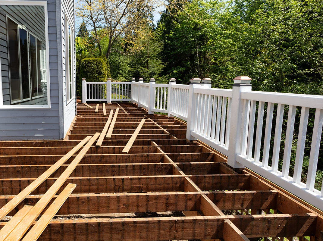Deck framing with white vinyl railing overlooking wooded landscape