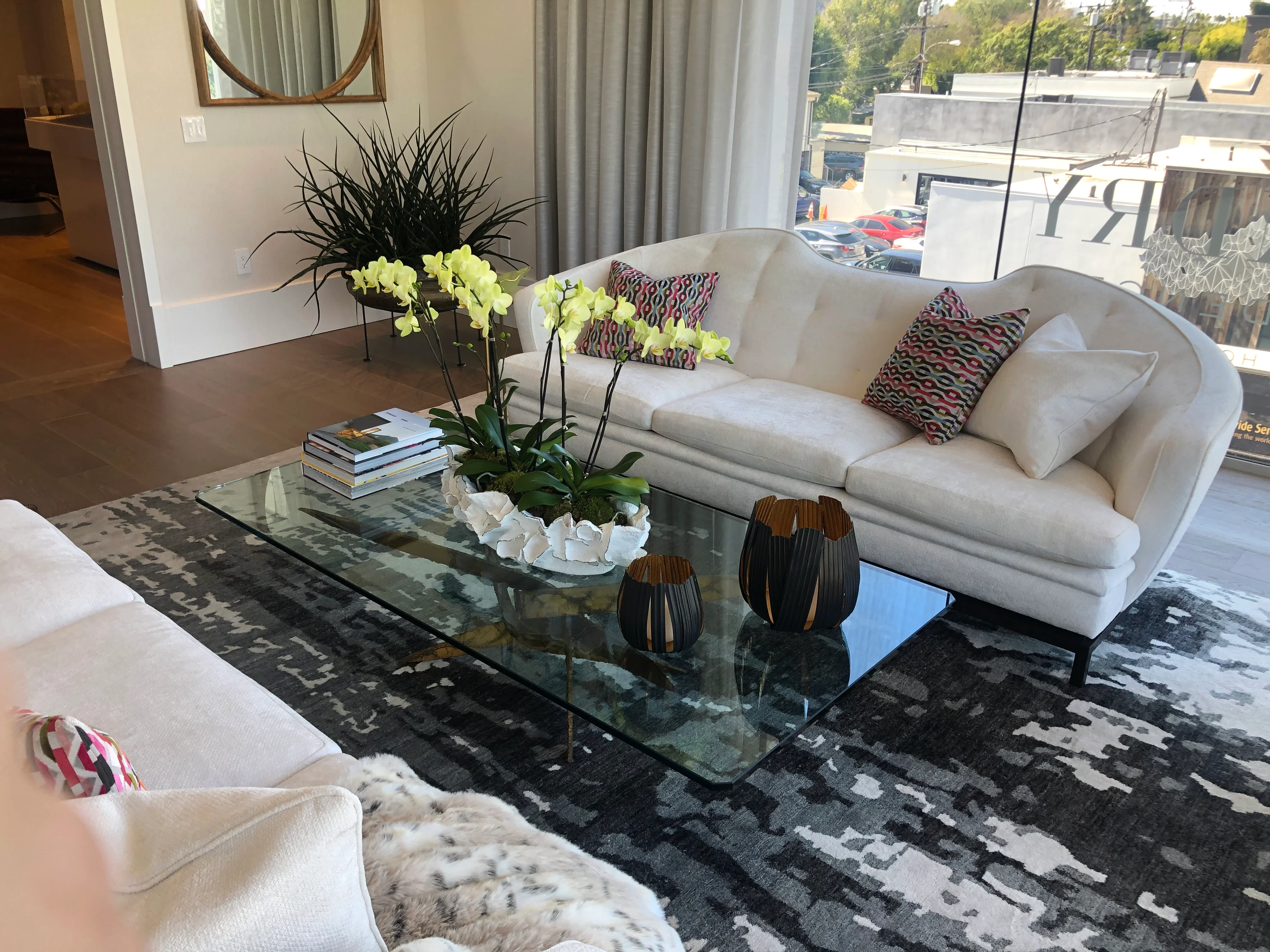 Modern living room with cream sectional, glass coffee table, and black patterned rug