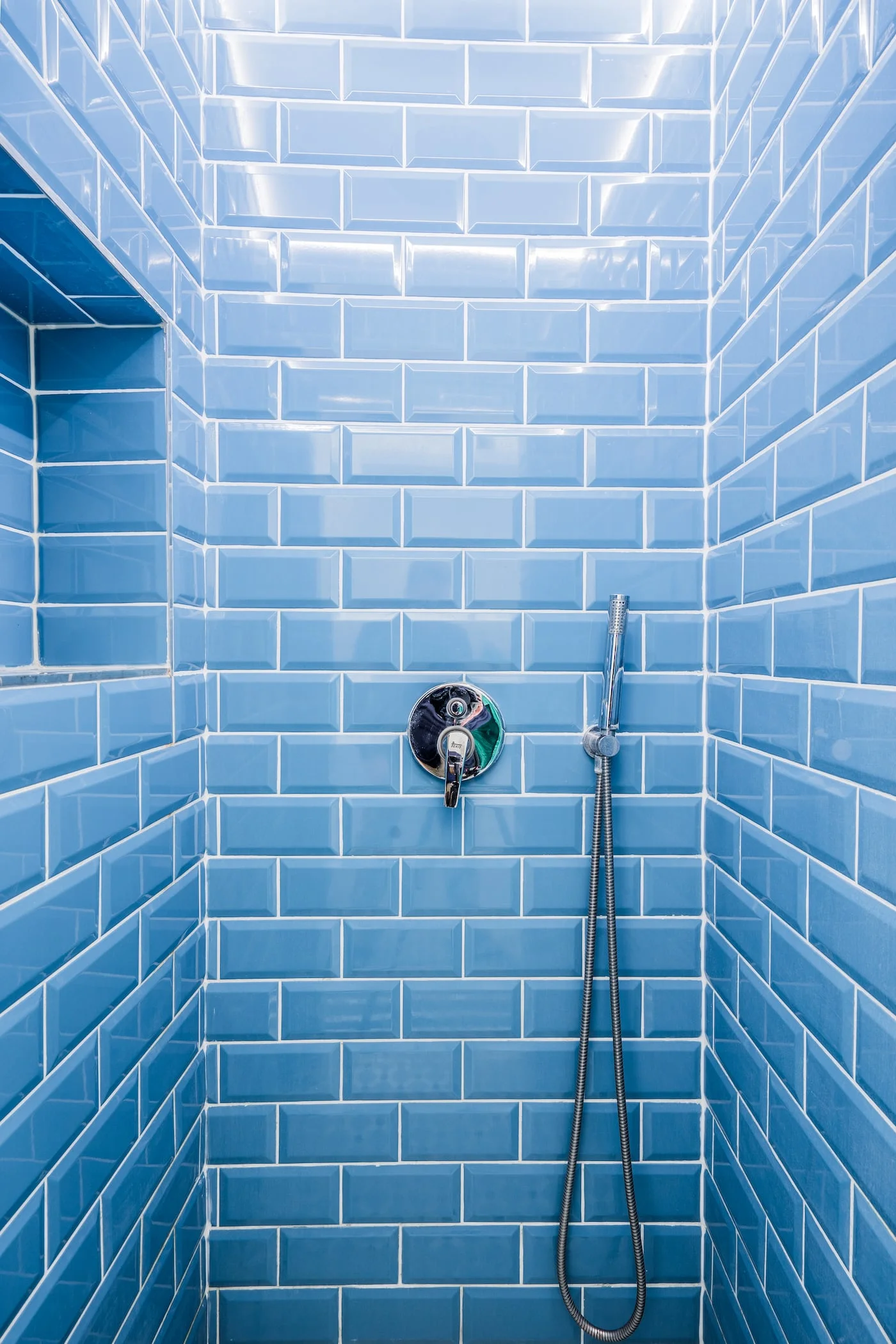Light blue subway tile bathroom with chrome shower fixtures and white grout lines