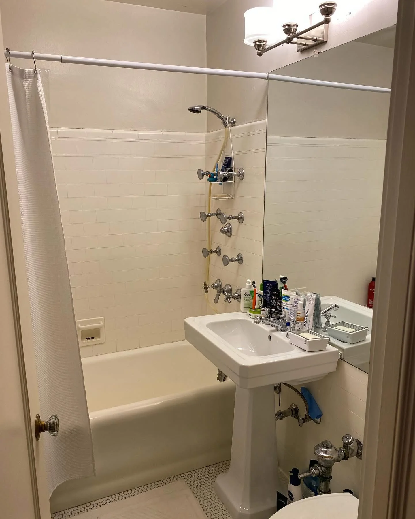 Renovated bathroom with white subway tile surround, pedestal sink, and chrome fixtures