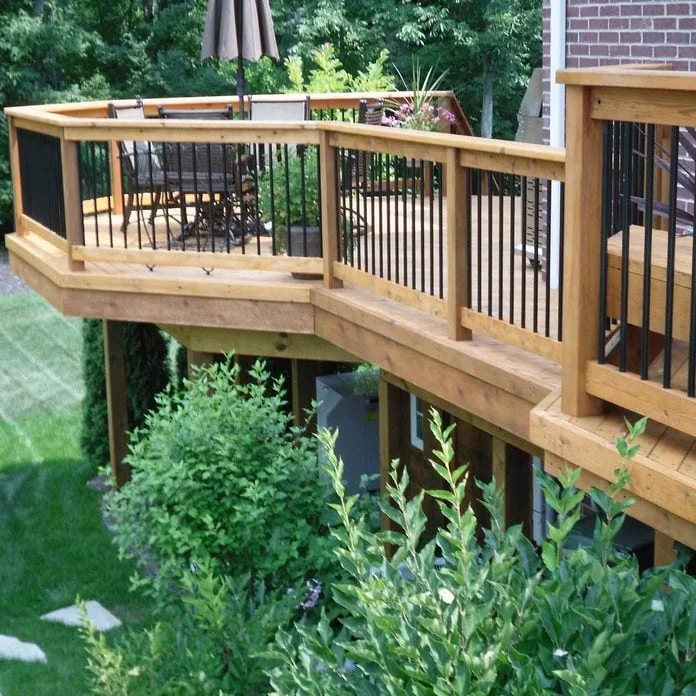 Elevated wooden deck with black metal railings overlooking landscaped yard