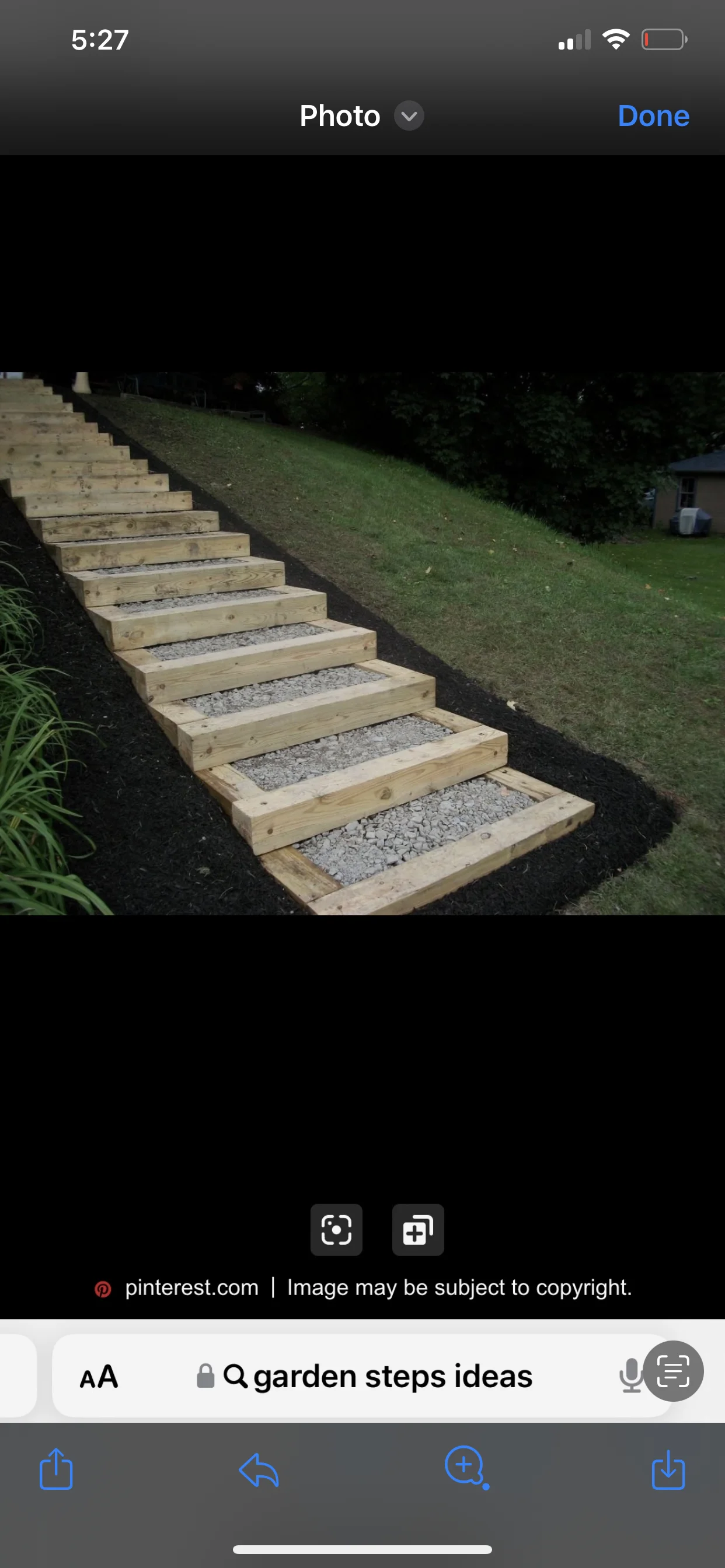 Wooden landscape stairs with gravel treads descending a grassy slope at dusk