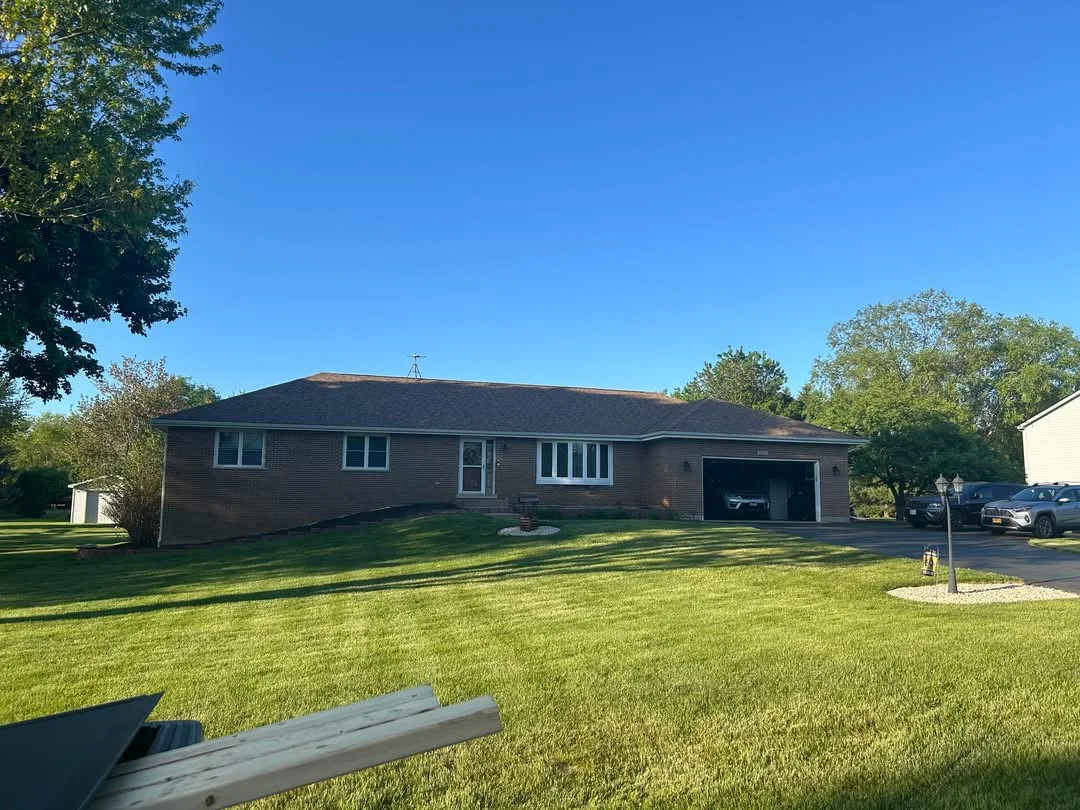 Brick ranch home with new charcoal gray asphalt roof and manicured lawn