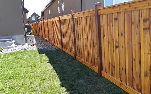 Cedar privacy fence with vertical boards and copper caps along residential property