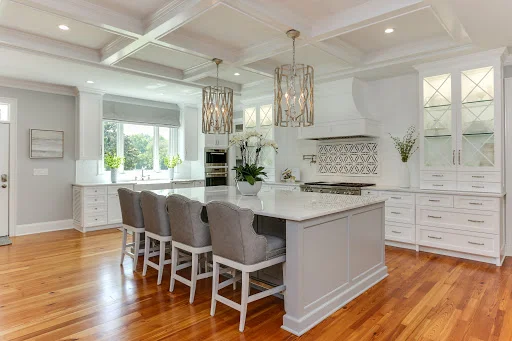 Modern white kitchen with island, pendant lights, and coffered ceiling in Barrington home