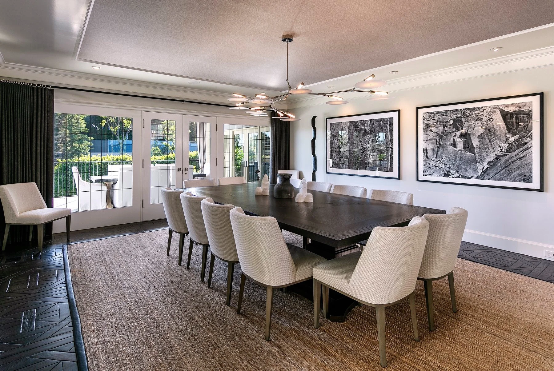 Modern dining room with black table, cream chairs, and glass doors overlooking terrace
