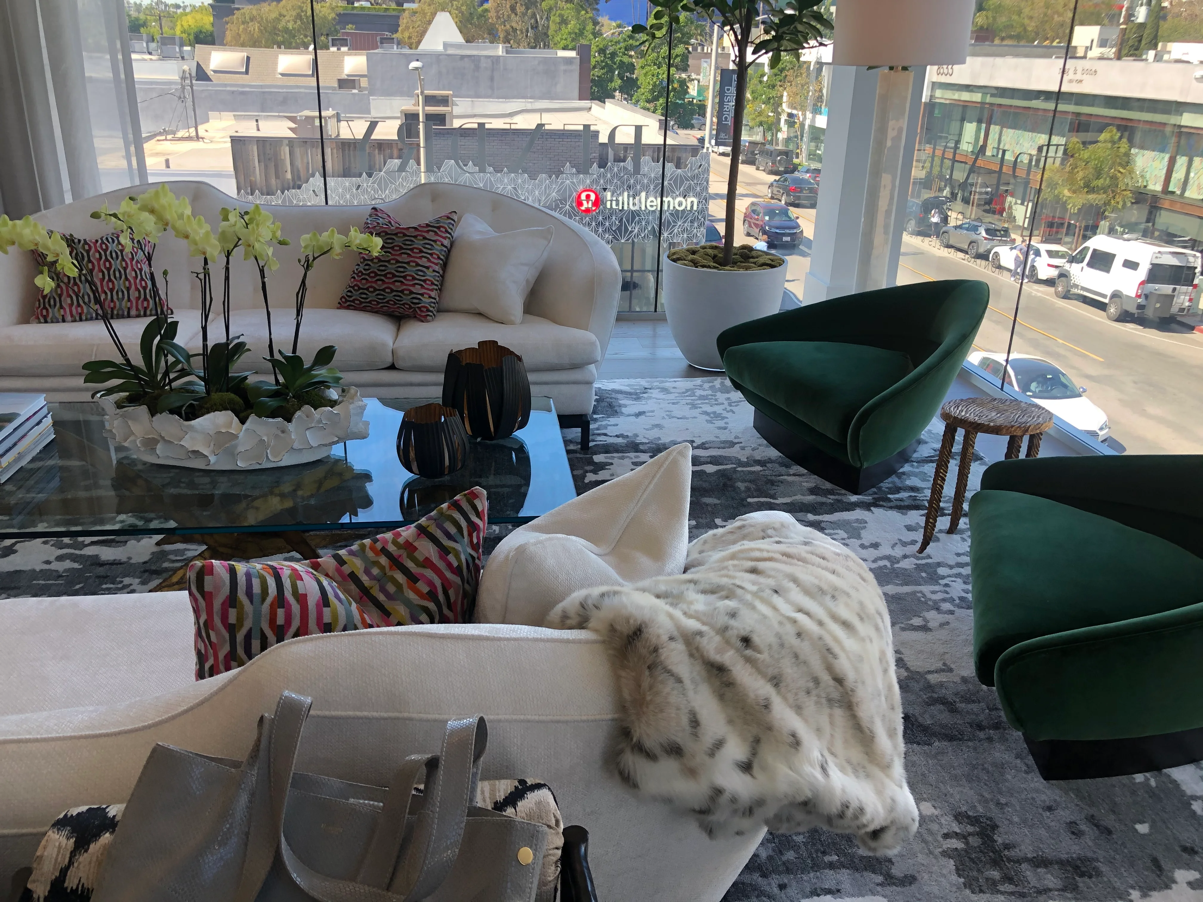 Modern showroom with cream and green furniture, glass table, and decorative accents
