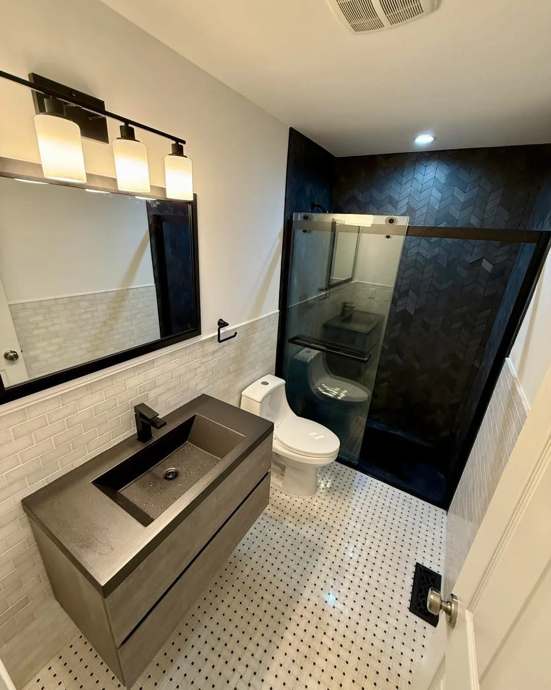 Modern bathroom with concrete vanity, subway tile, and dark herringbone shower wall