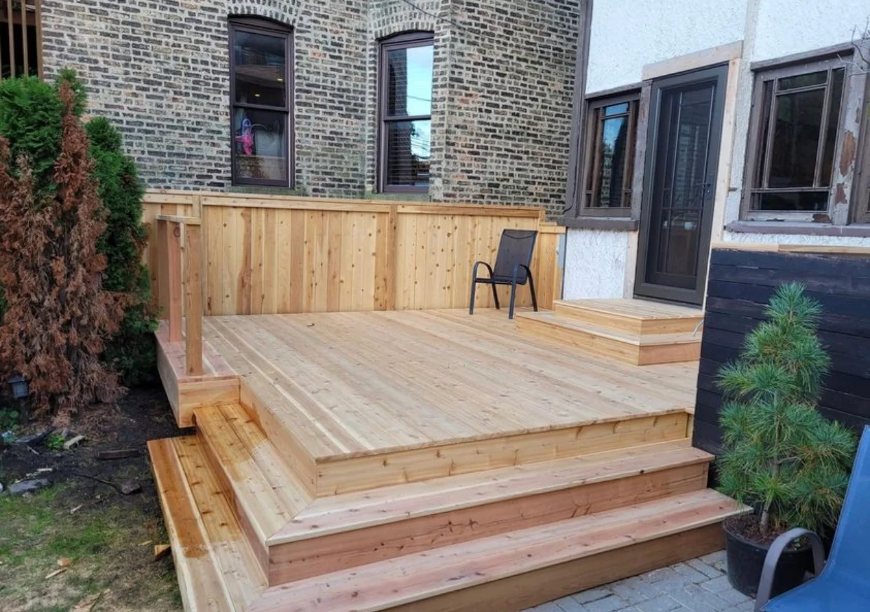New cedar deck with built-in seating and railings against brick home