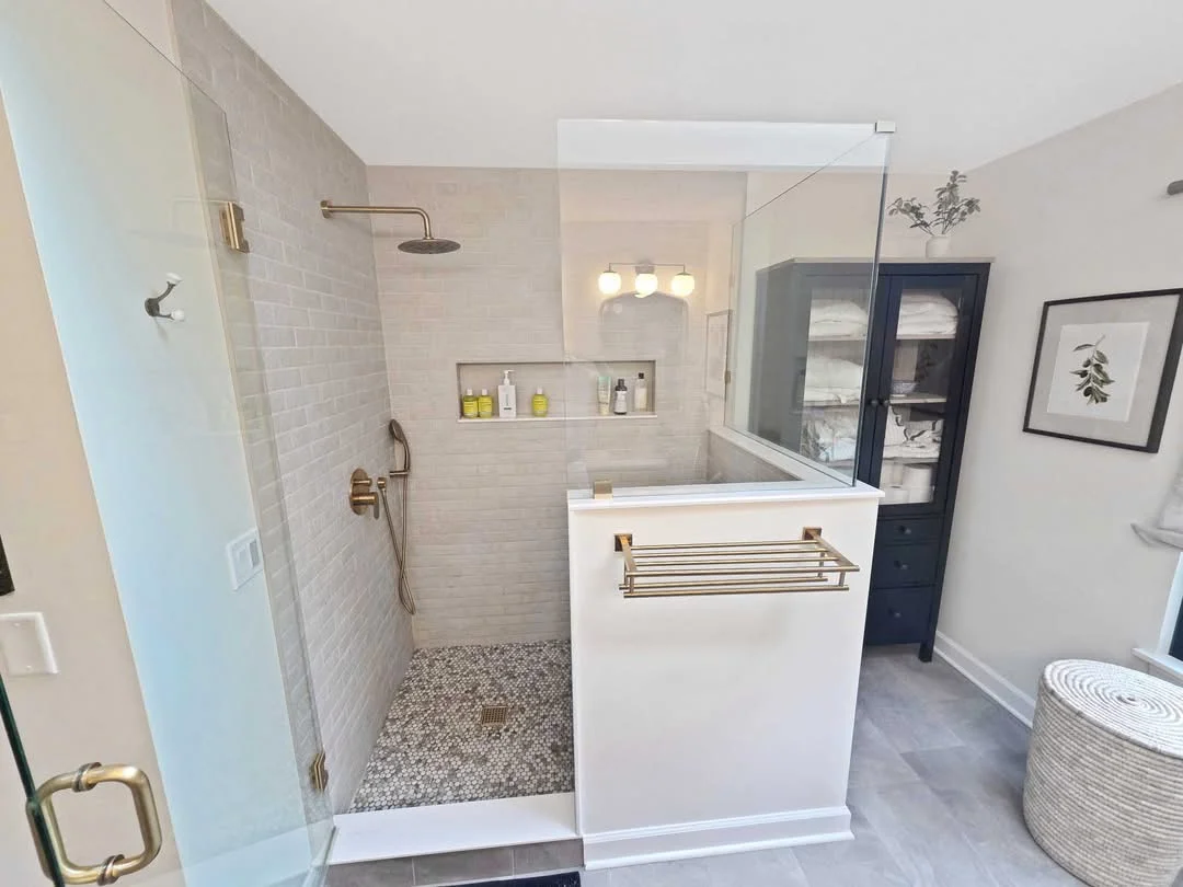 Modern bathroom with walk-in shower, white vanity, and navy storage cabinet