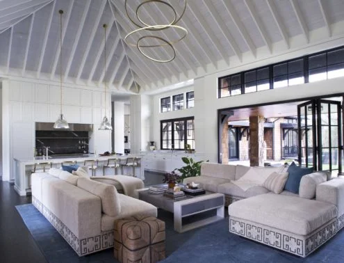 Modern kitchen and living room with vaulted ceiling, white cabinetry, and contemporary furnishings