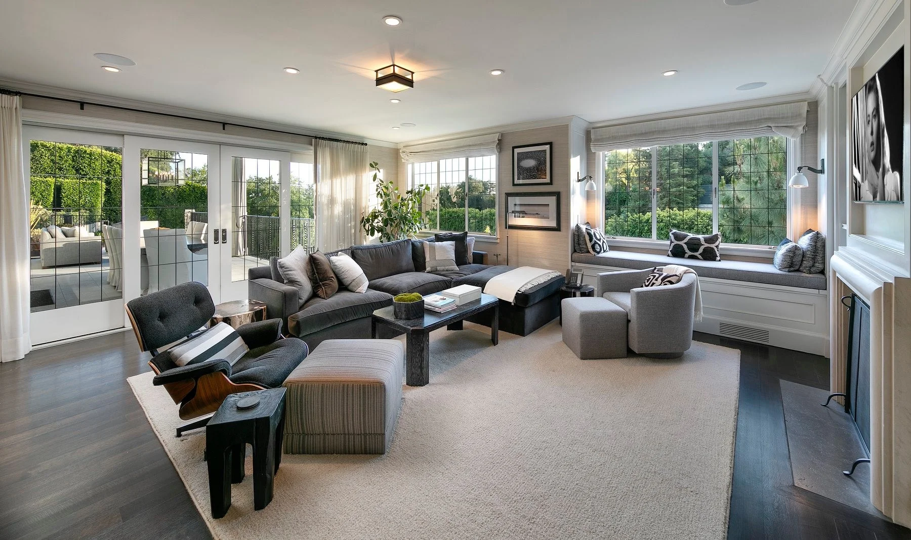 Modern living room with gray sectional, built-in window seat, and glass doors opening to patio