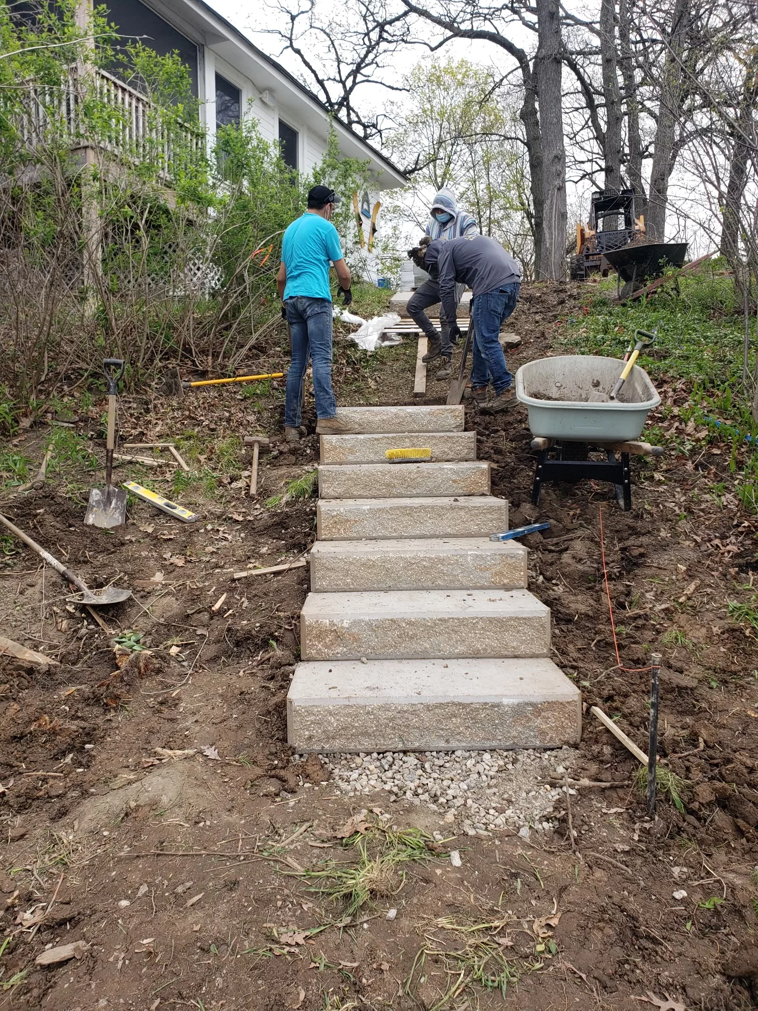 Concrete stepped walkway installation with landscape grading and soil preparation on residential property