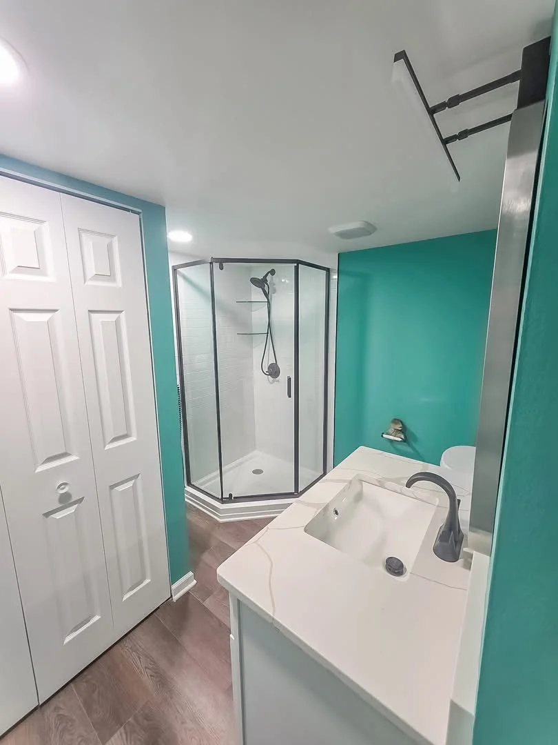 Modern bathroom with turquoise walls, frameless glass shower, and white vanity sink